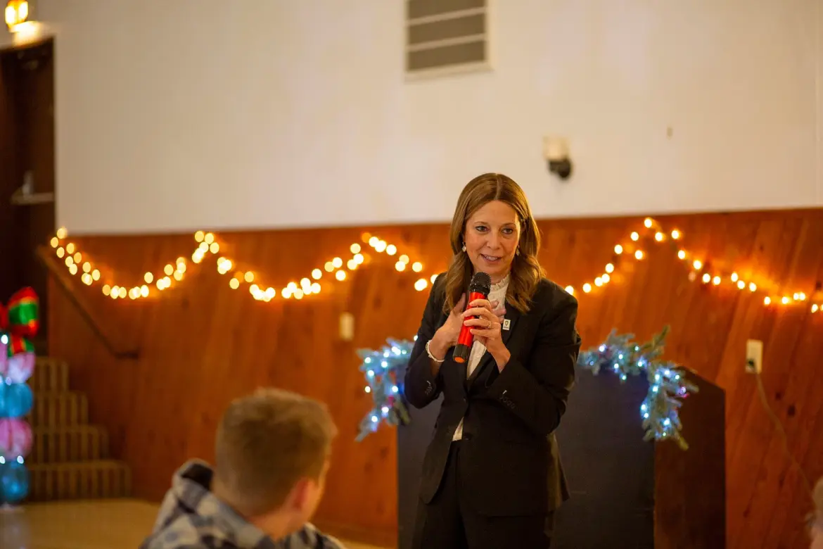 Amy Acton holding a microphone while addressing an audience indoors.